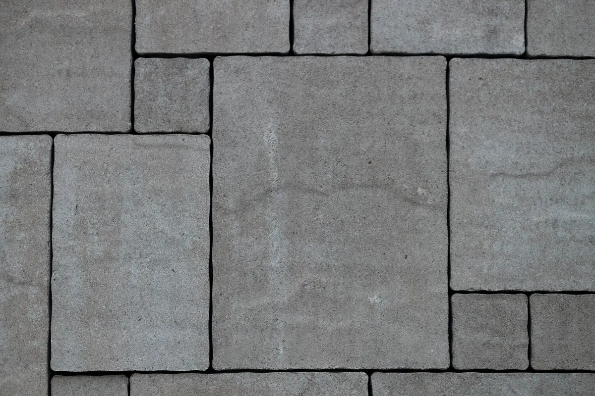 Vue de dessus de dalles grises de plusieurs formats, carrés et rectangles imbriqués en opus romain, joints sombres